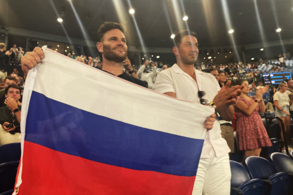 Russian fan Eugene Routman (left) and his friend Duran Raman hold up the Russian flag after Daniil Medvedev’s win on Rod Laver Arena. 