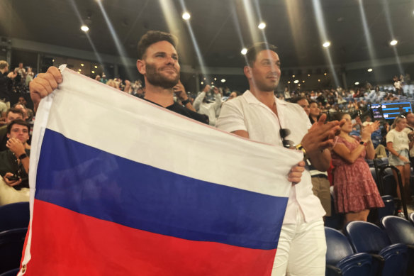 Russian fan Eugene Routman (left) and his friend Duran Raman hold up the Russian flag after Daniil Medvedev’s win on Rod Laver Arena.