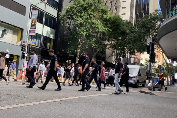 Pedestrians crossing the intersection of Elizabeth and Albert streets, where the bike lane separator is.