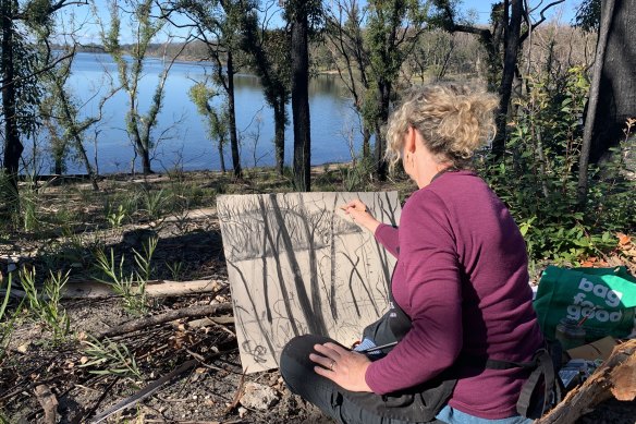 Penny Lovelock sketches with charcoal in the ruins of Lake Conjola.