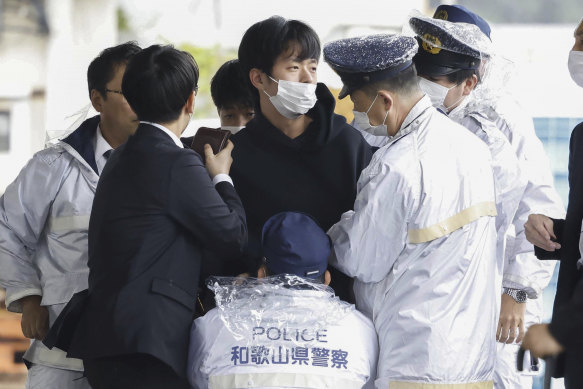 A man, centre, who threw what appeared to be a smoke bomb, is caught at a port in Wakayama, western Japan on Saturday.