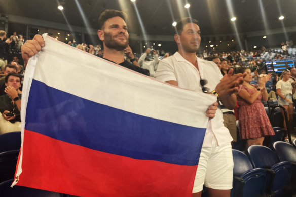 Russian fan Eugene Routman (left) and his friend Duran Raman hold up the Russian flag during week one of the Open.