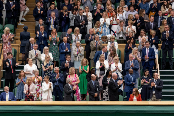 Royals and spectators stand for Oxford Professor Sarah Gilbert (seated in red, bottom right) on the opening day of Wimbledon. 