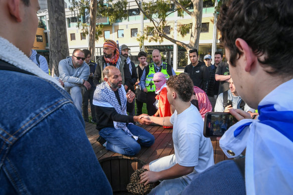 An Israeli supporter and Palestinian supporter shake hands after they sit down to discuss the war in Gaza at the Monash encampment.