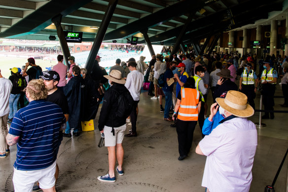Inside the SCG, people crowd under the stadium to get out of the rain.
