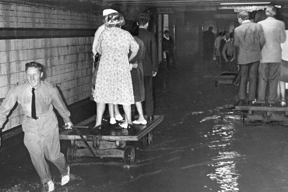 People were pulled along on railway trolleys to get through the flooding in the subway at Flinders Street station.