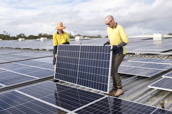 Workers install a rooftop solar panel in Queensland earlier this year. Household power generation is proving a challenge for retailers around the country.