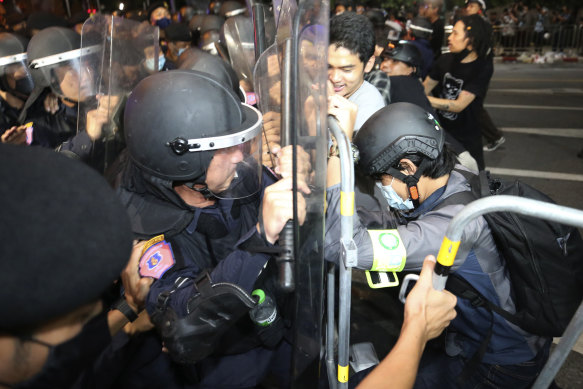 Pro-democracy protesters push Thai police officers with riot shields during a demonstration in Bangkok on Thursday morning. The police dispersed a group of protesters holding an overnight rally outside the Prime Minister's office.