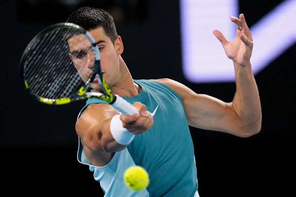 Carlos Alcaraz plays a forehand return to Novak Djokovic.