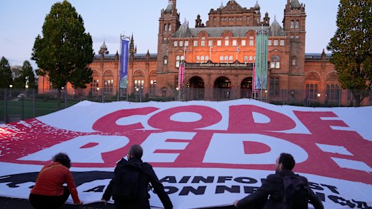 Climate activists unfurl a large “Code Redd” banner outside the climate talks in Glasgow.