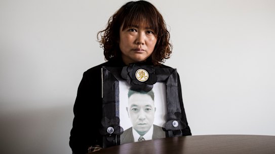 Lihong Wei holds a portrait of her husband Xiaojun Chen, who was killed while working for a delivery company in Sydney in September.