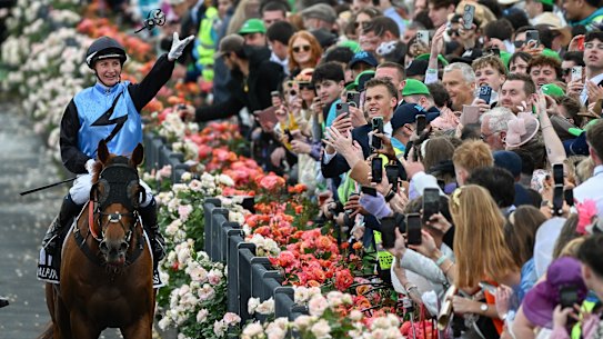 Jamie Melham throws her race goggles into the crowd after winning the Melbourne Cup on Half Yours.