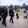 Police officers carry long-arm guns around the foreshore.