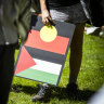 Flags and placards showing Indigenous solidarity with Palestine at a Melbourne rally.