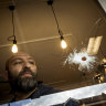 Cafe owner Fidel Takla surveys the bullet holes at his cafe.