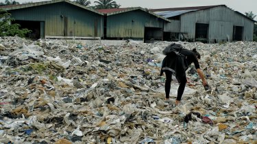 A member of the Kuala Langat environment NGO picks up  plastic waste at a shuttered illegal plastic recycling factory in Jenjarom. 