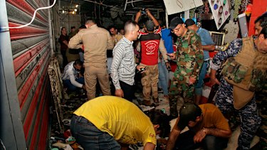 People and security forces gather at the site of a bombing at a market in Sadr City, Iraq.