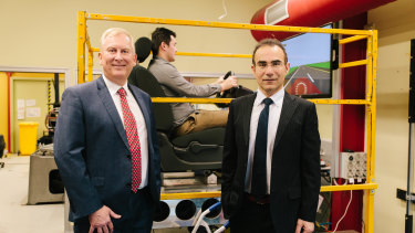 Professor Stephen Robinson and Associate Professor Mohammad Fard stand in front of the simulator. 
