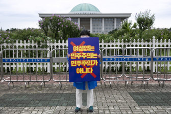 Kim Je-hee, a nurse who has organized rallies denouncing anti-feminists, holds a sign reading ‘Democracy without women is no democracy’ outside the National Assembly in Seoul, in August.