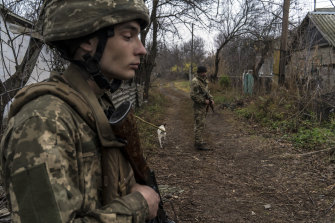 Ukrainian soldiers patrol a street that runs parallel to the Kalmius River, which divides Ukrainian government-controlled territory from non-government-controlled areas, in Hranitne, Ukraine.