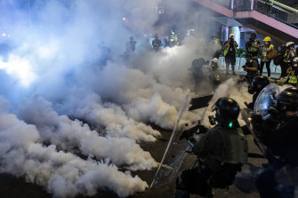 Riot police walk toward a cloud of tear gas as they attempt to disperse demonstrators during a protest in the Sheung Wan district of Hong Kong.