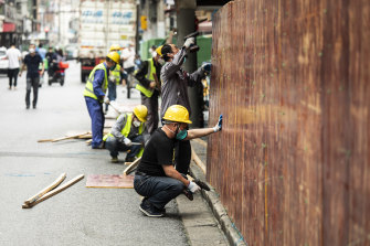 İşçiler, karantina altına alınan bir mahalleyi çevreleyen bariyerleri kaldırır.