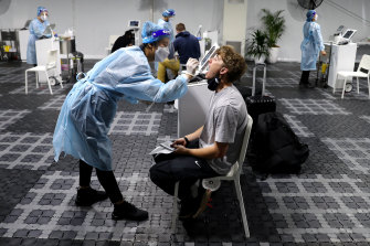 A traveler will receive a COVID-19 test prior to his flight at a Histopath test clinic at Sydney Airport on Tuesday.