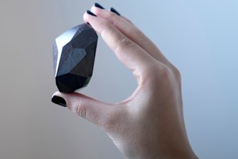 An employee of Sotheby’s Dubai presents a 555.55 carat black diamond “the Enigma”.