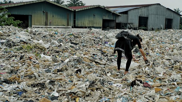 A member of the Kuala Langat environment NGO picks up  plastic waste at a shuttered illegal plastic recycling factory in Jenjarom. 
