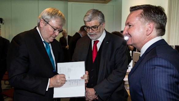 Former Prime Minister Kevin Rudd signs a copy of his new book ‘The PM Years’ for Senator Kim Carr as Shadow Treasurer Chris Bowen watches on.
