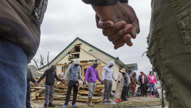 Residents of Talibotton, Georgia, pray outside a destroyed home.