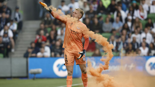 Melbourne City goalkeeper Tom Glover picks up a flare to remove it from the field.