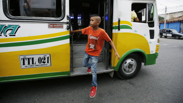 Young Venezuelan migrant Jhon Jader Duno exits a bus after begging for money from commuters in Cucuta, Colombia. Duno said he's trying to raise enough money for he and his mother to move on to another city.