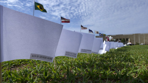 The names of people who died of COVID-19 cover white flags in a field as part of a protest against the government’s health policies outside the National Congress in Brasilia, Brazil.