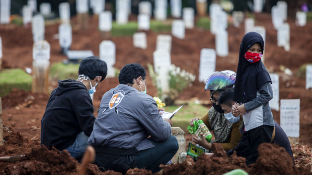 Relatives visit the grave of a COVID-19 victim. The health crisis has forced President Joko Widodo to park his reform agenda.
