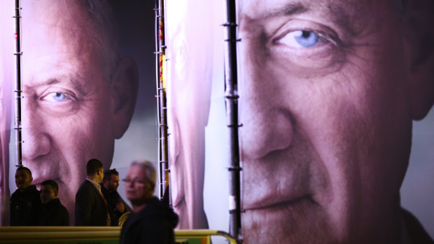 People walk by posters of retired Israeli military chief Benny Gantz  for his election campaign for the April 2019 elections, in Tel Aviv.