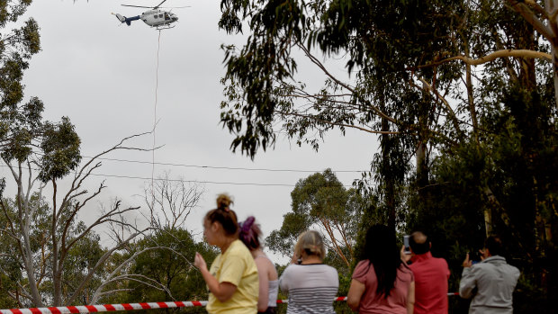 Residents watch on as a water bomber helicopter is seen as a fire burns out of control near Voyager Point, Sydney