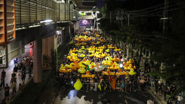 Protesters march while carrying inflatable yellow ducks outside the headquarters of army regiment in Bangkok, Thailand. 
