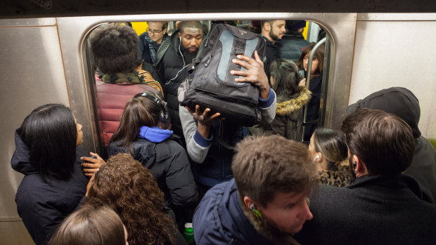 Commuters struggle to enter and exit a subway car on the L train in New York. 