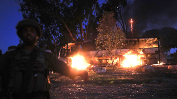 An Israeli soldier stands near a burning bus after it was hit by a mortar shell fired from Gaza on Monday. 