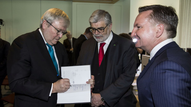 Former Prime Minister Kevin Rudd signs a copy of his new book ‘The PM Years’ for Senator Kim Carr as Shadow Treasurer Chris Bowen watches on.