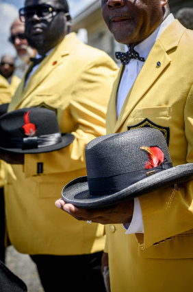 Zulu members hold their hats as Leah Chase's coffin is carried out of St Peter Claver Catholic Church. 