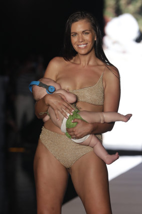 Model Mara Martin walks down the runway while breastfeeding her baby during the Sports Illustrated swimwear show at Miami Swim Week, Sunday, July 15, 2018.
