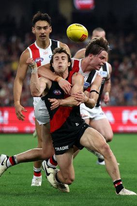 Andrew McGrath gets a handball away for the Bombers under pressure from St Kilda’s tacklers.