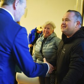 Auctioneer David Wood (left) greets buyer Carmen Szabo and her son, who bid on her behalf.