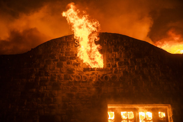 Flames escape from the broken window of a burning building at the Soda Rock Vineyards during the Kincade fire in Healdsburg, California.