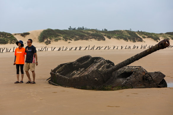 People pose for pictures with an abandoned American M18 army tank  at Ou Cuo Beach in Kinmen.
