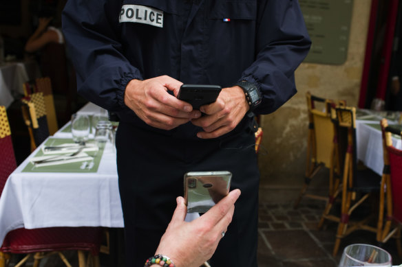 A police officer conducts a customer health pass check, enforced under new nationwide legislation, at a restaurant in Paris, France.