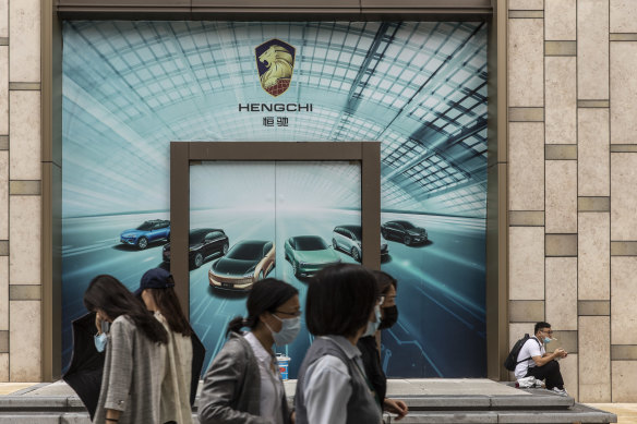 People walking in front of a yet to be opened showroom for China Evergrande New Energy Vehicle Group’s electric vehicles in Shanghai in mid-September.