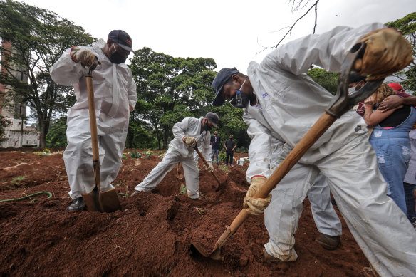 Workers wearing protective gear bury the casket of a COVID-19 victim  in Sao Paulo, Brazil, on Friday. The country has lost more than 200,000 people to the new coronavirus.